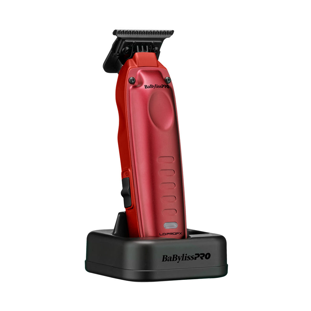 A red BabylissPRO+ cordless hair trimmer standing upright on a black charging base against a plain white background.