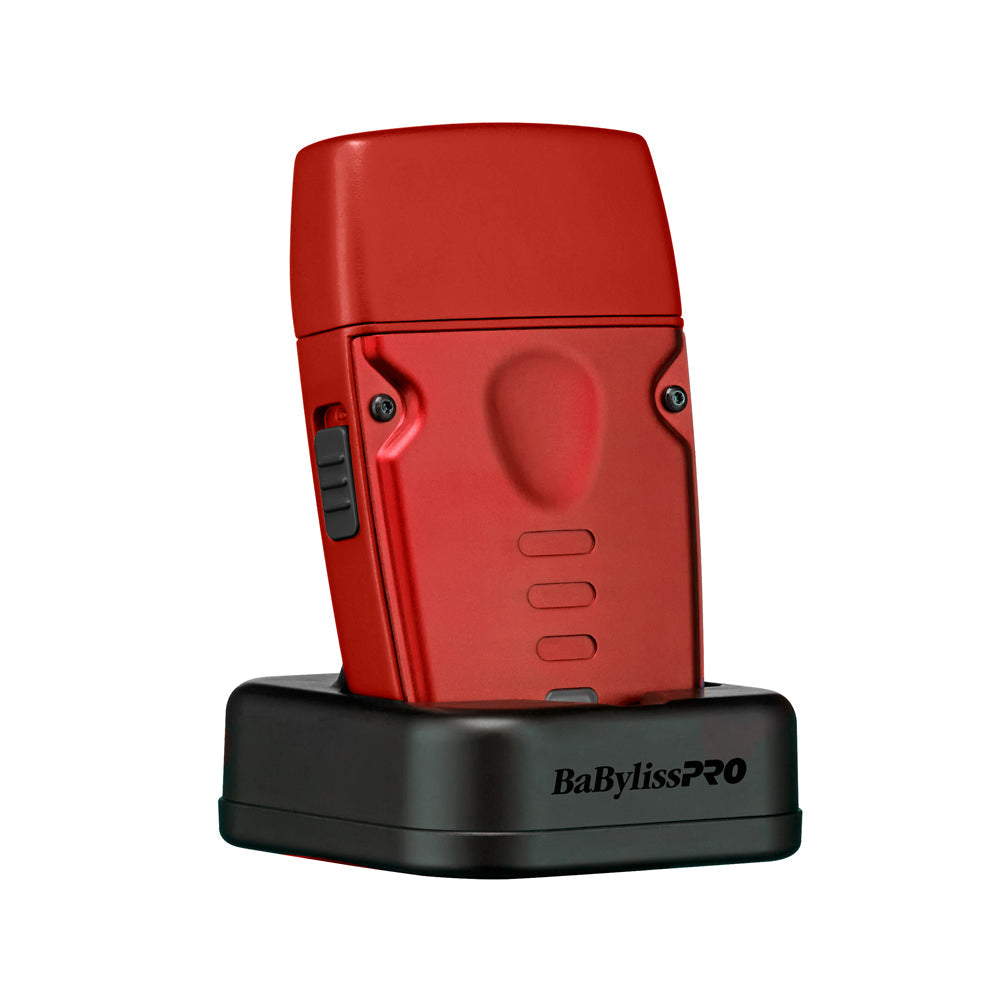 A red BaBylissPRO shaver standing upright on a black charging dock against a solid white background.