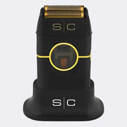 A black electric shaving device with gold accents, including a gold rotary shaving head and gold 'S|C' branding, shown on its matching black charging dock against a light gray background.
