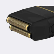 Black and gold electric shaver on a light gray background